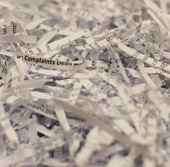 Close-up view of a pile of shredded paper pieces with fragments of text visible on some of the strips.